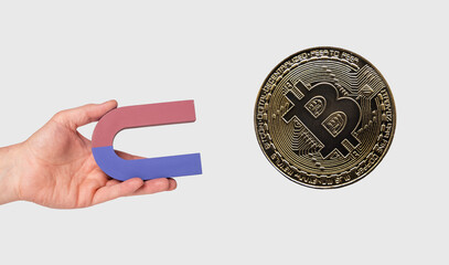 Hand holding magnet and attracting bitcoin. Cryptocurrency, digital money concept. High quality...