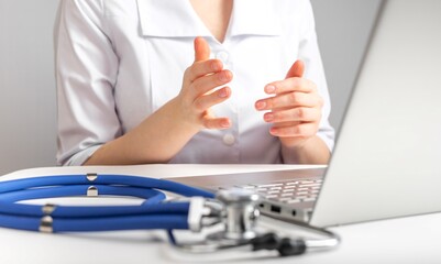 Doctor giving online consultation to patient. Healthcare and telemedicine concept. Remote client examination and treating diseases. Woman in lab coat sitting at desk with laptop and stethoscope. photo