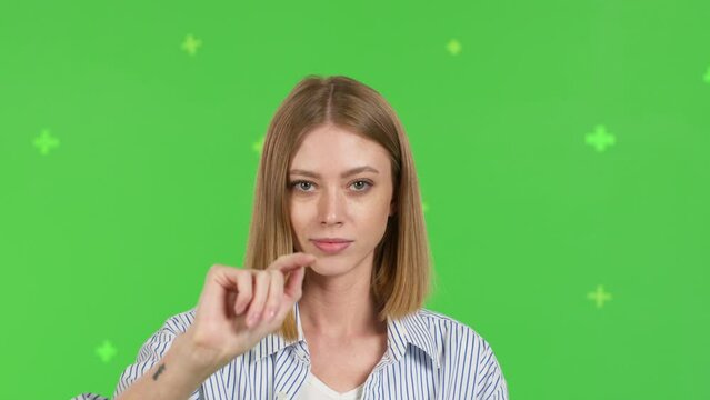 Close-up of young woman swipes finger at display of phone. Female over green screen background, Chroma Key. 4k video footage