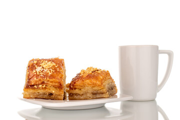 Sweet baklava classic with a cup on a ceramic saucer, macro, isolated on a white background.