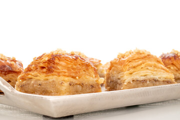 Sweet baklava classic on a metal tray, macro, isolated on a white background.