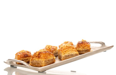 Sweet baklava classic on a metal tray, macro, isolated on a white background.