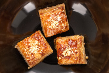 Sweet baklava classic on a ceramic plate, close-up, top view.
