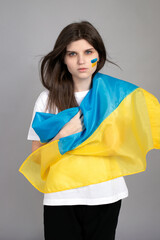 Portrait of a serious Ukrainian woman with a blue and yellow Ukrainian flag in her hands. National...
