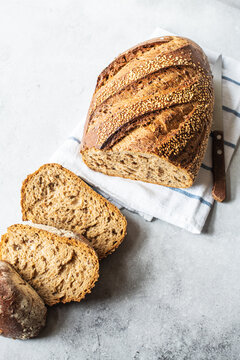 Sliced rye sourdough bread with nuts and sesame on a gray background. Top view.