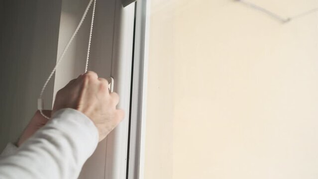 Close up man hand opening horizontal window blinds with copy space. 