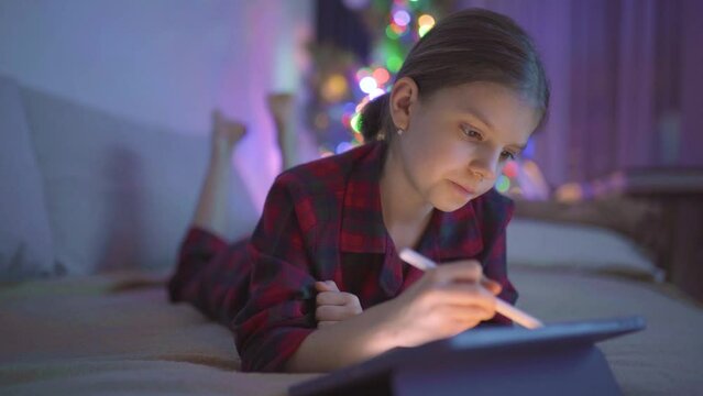 Teen girl is drawing or writing diary in bedroom by tablet with digital pen