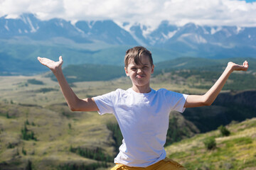 A child funny boy on the Altai mountain background. Concept of tourism, travel, lesure and freedom. Altai mountain, beauty summer evening landcape