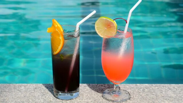Fresh summer tropical cocktails drinks near swimming pool in modern luxury resort. Vacation, travel, holidays in Thailand. Drink a cocktail on vacation on edge of the blue pool. Poolside party