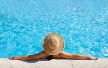 Fototapeta na wymiar top view of woman in straw hat relaxing in swimming pool