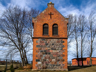 Fototapeta premium General view and architectural details of the Catholic church of Saint John the Baptist with a belfry built at the turn of the 19th and 20th centuries in the village of Targowo in Masuria, Poland.