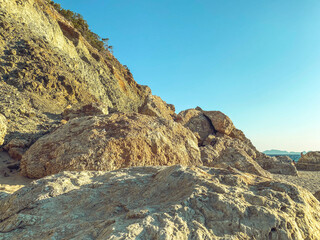 huge stones lie on the beach near the sea. huge boulder of sand, rock. a stone lies on the seashore and is washed by water against the background of a blue sky