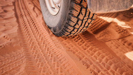 4wd vehicle tyre, dirty from dust - track print visible in red sand, closeup detail