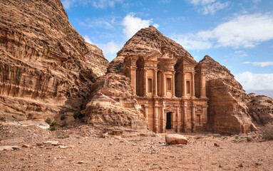 Ad Deir - Monastery - ruins carved in rocky wall at Petra Jordan, mountainous terrain with blue sky...