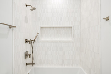 Contemporary Bathtub Enclosure with Gold Fixtures. White and gray tiled bathtub surround with gold...