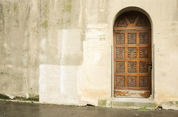 An old wooden one leaf cassette door in a plastered wall that is painted in different ocher colors...