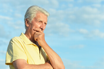 Thinking senior man posing in summer park