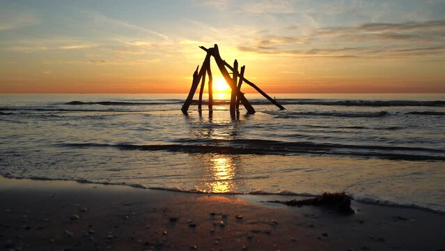 Sunset at the beach with a pile of wooden sticks in focus