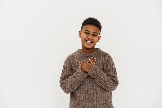 Black preteen boy smiling and holding hands on his chest