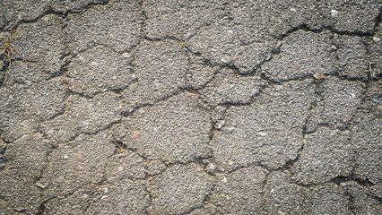 Crack on the asphaltic surface. Natural pattern on textured surface. Ruined of the walkway.
