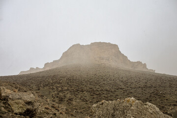 brown rock hill behind fog and step