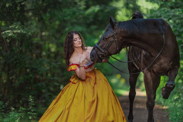 A young woman in a vintage yellow dress walks with a brown horse in a green park on a summer day