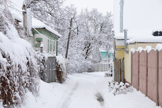 Street in the snow with one-story houses in the snow and roads along the street in Ukraine in the city of Dnipro, winter