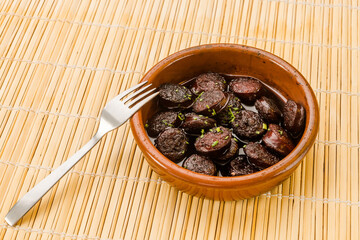 Typical Spanish food, portion of chorizo ​​in wine. 
Horizontal view of food in a clay pot.