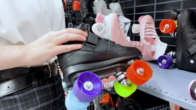 Someone chooses retro style roller skates black with multicolored wheels in the sports goods store 