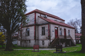 Three story old centuries wood house with stone basement and green garden with grass and big trees...