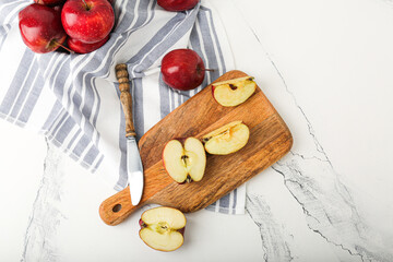 Fresh ripe whole and peeled red apples with cutting board and knife on stone table