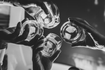 Cheers! Close up of men celebrate and raise glasses of whiskey drink alcoholic beverage in the pub....