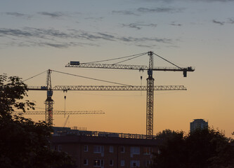 Two tower cranes at sunset.