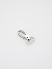 The heap of metal lobster claw clasp for making bags and backpacks lying on a gray background. Chrome-plated metal accessories and supplies for bags, backpacks. Handbags making, copy space