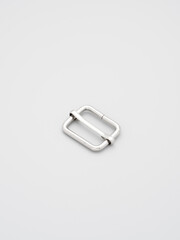 Metal adjusters and frames for making bags and backpacks on a grey background. Chrome-plated metal frames for handbags straps. Sewing accessories, bags making