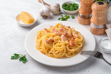 Italian linguini pasta with carbonara sauce made from bacon, parmesan, egg and pepper on a grey background.