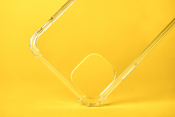 Close-up of a transparent silicone case for a smartphone on a yellow background.