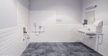 The interior of bathroom with facilities for the disabled. White bricks. Grey tile.