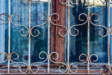 The window of an old house behind a metal patterned lattice.