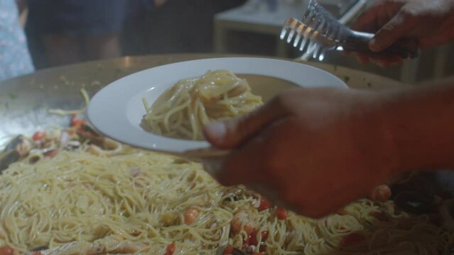 08.10.2021 Borgagne, Puglia, Italy. Pasta with seafood closeup. The hands of the cook put the dish on the plate. Home cooking in a Italian restaurant. Delicious and healthy food for dinner.