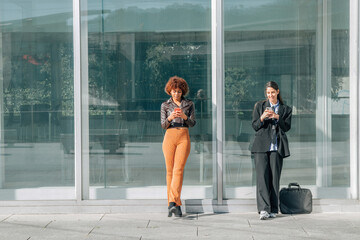 business and urban woman with mobile phones in the street