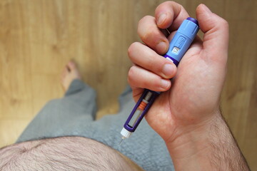 Overweight man applying diabetes medicine injection (syringe) into his stomach, belly