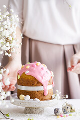 A woman's hand decorates an Easter cake with a confectionery sprinkling. The concept of the Easter holiday