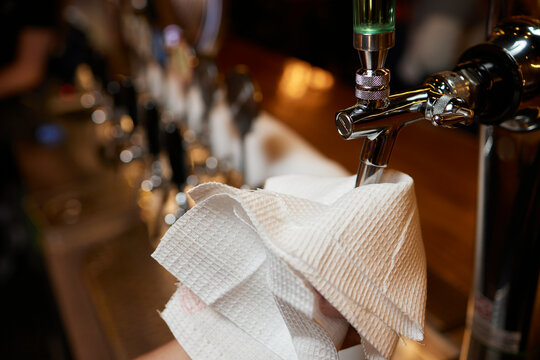 Waiter or bartender cleaning beer taps on the counter in pub and restaurant.