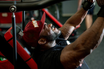 Strong muscular man doing exercises in gym. Handsome athletic bodybuilder working out.