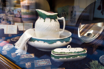 A large porcelain white and green water pitcher adorns a vintage display case.
