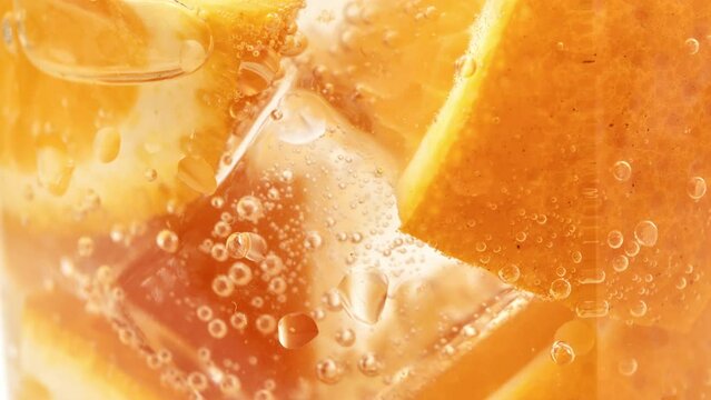 Fresh orange cocktail fruit pulp texture ice cubes fizzy bubbles in glass slow motion closeup