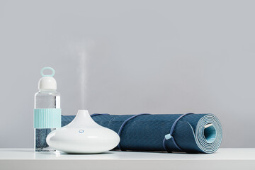 Rolled blue yoga mat and essential oil diffusor for enhanced practice. Ultrasonic and humidifying...