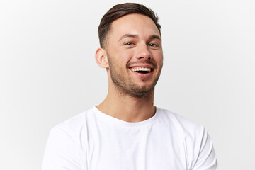 Fototapeta premium Joyful cute happy young tanned handsome man in basic t-shirt laugh at camera posing isolated on over white studio background. Copy space Banner Mockup. People emotions Lifestyle concept. Portrait