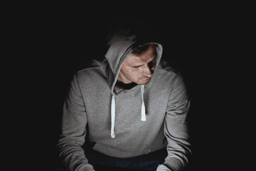 man in a gray hoodie at black background
